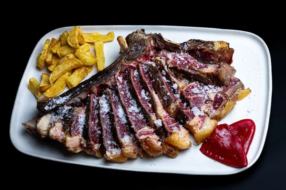 Chuletón troceado con patatas fritas y pimientos asados