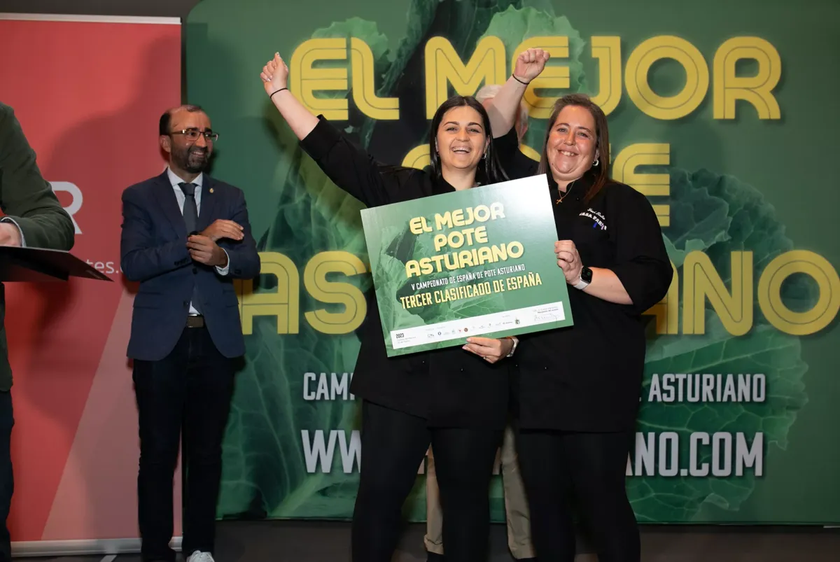 Dos mujeres recogiendo y celebrando el premio al Tercer Mejor Pote Asturiano de España