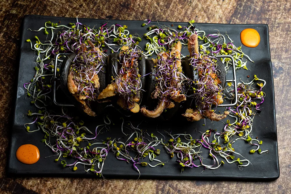 Pan bao negro con calamares y brotes